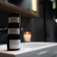 Drei Balsamtiegel stehen aufeinander gestapelt auf dem Waschbeckenrand