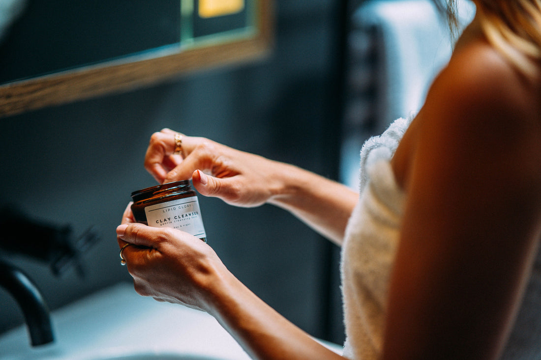 Frau im Badezimmer entnimmt Balsam aus Tiegel