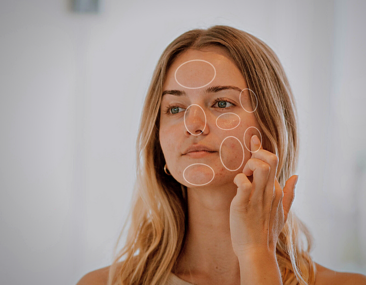 Das Spiegelbild einer Frau mit Zonen im Gesicht, die durch Kreise markiert sind