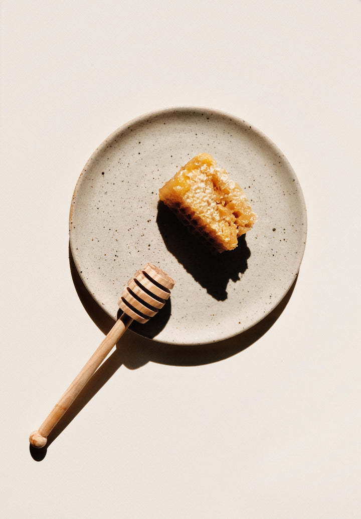 Honey and a spoon on a small plate