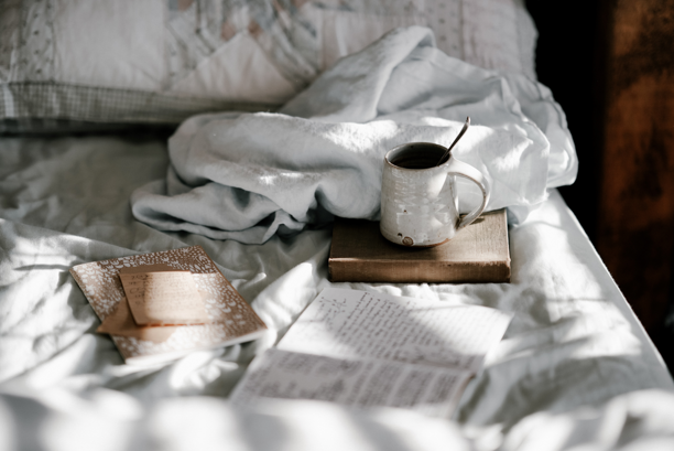 Books and a cup of tea on a cozy bed